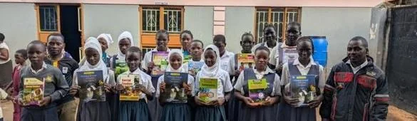 Students holding books and supply packs from the Amity Torch Program